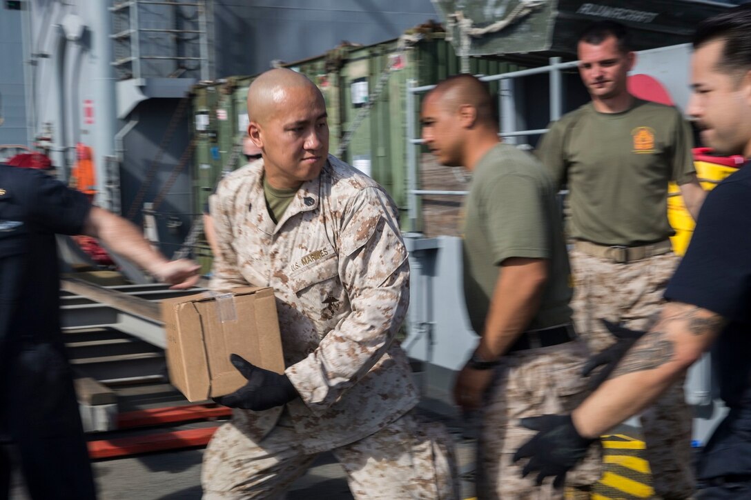 U.S. Marine Staff Sgt. Bau T. Le helps offload supplies during replenishment at sea aboard the USS Rushmore (LSD 47) at sea in the Pacific Ocean, May 31, 2015. Le is a supply chief with Combat Logistics Battalion 15, 15th Marine Expeditionary Unit. Marines and Sailors worked together to off load supplies and mail from loved ones. (U.S. Marine Corps photo by Sgt. Emmanuel Ramos/Released)