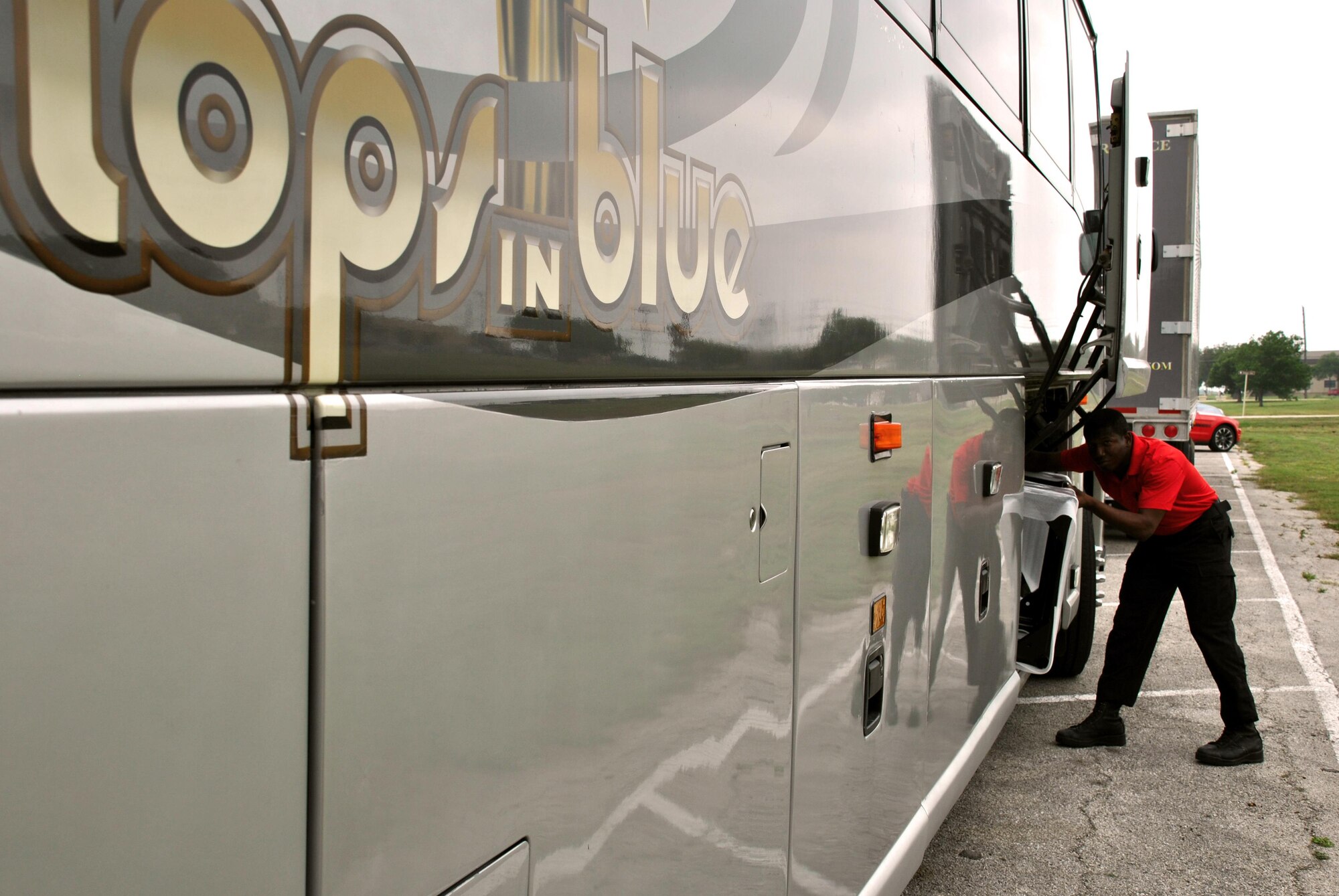 Staff Sgt. Ronald Brooks, one of two Tops In Blue vehicle operators, removes a piece of staging from beneath the motor coach that will carry performs to performances around the country. (U.S. Air Force photo/Debbie Aragon/Released)