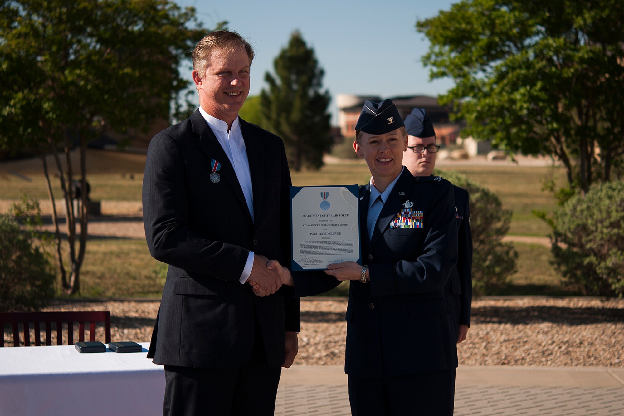 GOODFELLOW AIR FORCE BASE, Texas – Col. Kimberlee P. Joos, 17th Training Wing Commander, presents the Public Service Award to Paul Clever during a ceremony in front of the Norma Brown Building April 30. The award recognized Clever and his wife for their distinguished service in recovering human remains from a Vietnam crash site to confirm the identities of seven of the CAP-72 crewmembers who were shot down by enemy forces over southern Laos in 1969, one of whom was Clever’s father. (U.S. Air Force photo/ Airman 1st Class Devin Boyer)