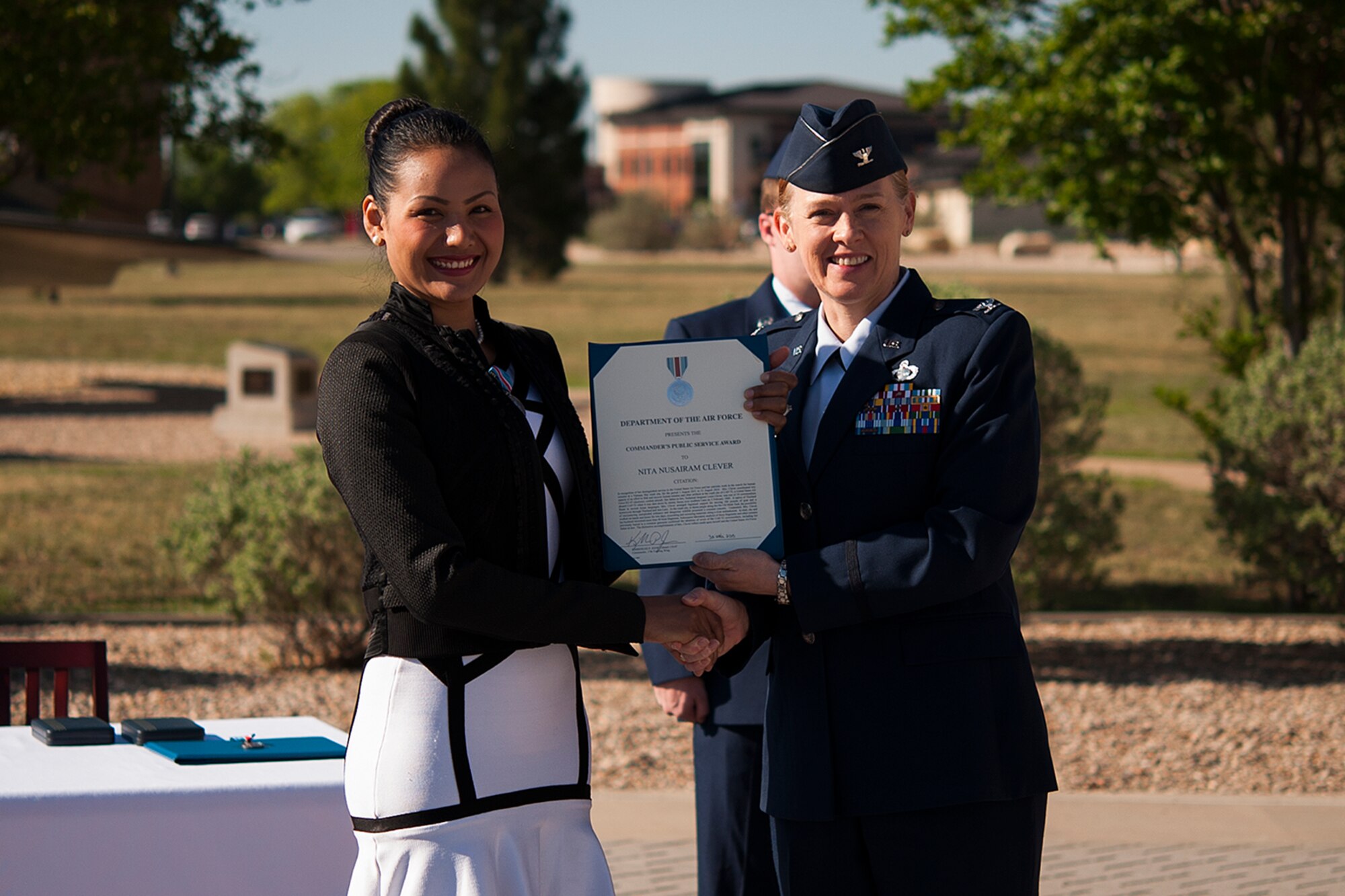 GOODFELLOW AIR FORCE BASE, Texas – Col. Kimberlee P. Joos, 17th Training Wing Commander, presents the Public Service Award to Nita Clever during a ceremony in front of the Norma Brown Building April 30. The award recognized Clever and her husband for their distinguished service in recovering human remains from a Vietnam crash site to confirm the identities of seven of the CAP-72 crewmembers who were shot down by enemy forces over southern Laos in 1969, one of whom was Clever’s father-in-law. (U.S. Air Force photo/ Airman 1st Class Devin Boyer)