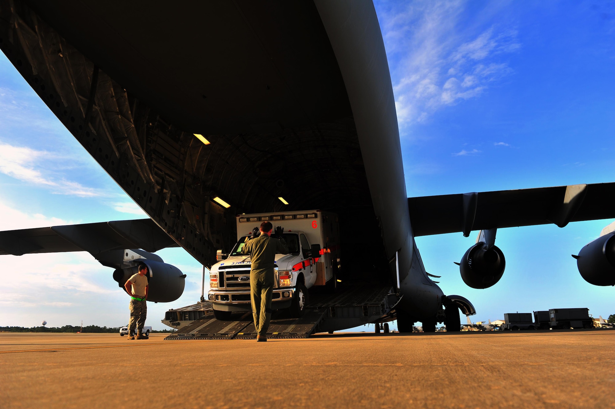 Tech. Sgt. Eric Blevins, 316th Airlift Squadron loadmaster, marshals an ambulance onto a C-17 Globemaster, May 27, 2015, at Hurlburt Field, Fla. The C-17, loaded with 823rd RED HORSE members and medical vehicles, took off in support of NEW HORIZONS 2015, an annual event conducted to train military civil engineers and medical professionals to deploy and conduct joint operations. (U.S. Air Force photo by Airman 1st Class Ryan Conroy/Released)  
