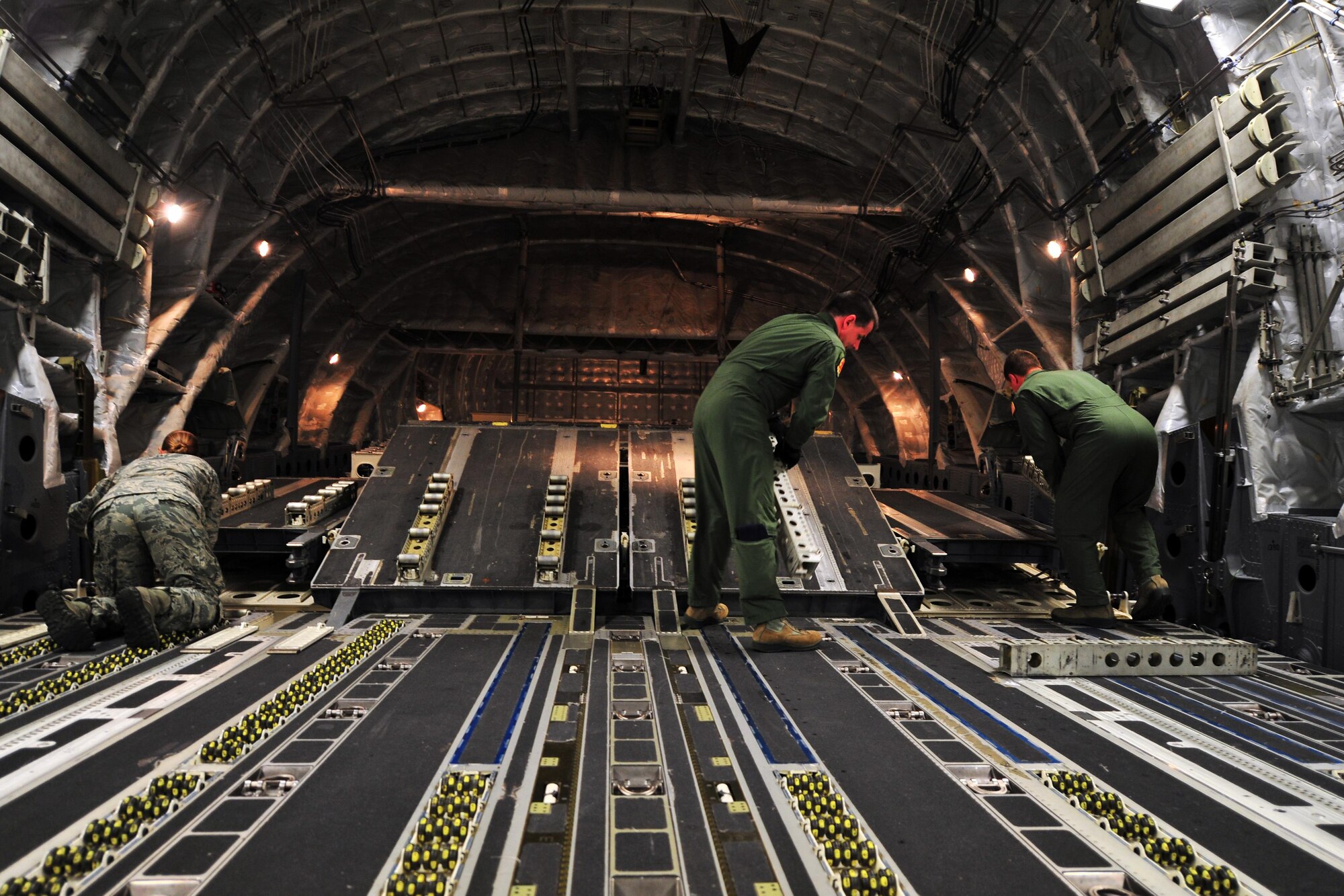 Loadmasters from the 316th Airlift Squadron flip cargo rollers on a C-17 Globemaster in preparation for incoming pallets, May 27, 2015, at Hurlburt Field, Fla. The Airmen loaded two ambulances and four pallets of cargo before taking off for NEW HORZIONS 2015. U.S. service members deployed to Honduras in support of NEW HORIZONS 2015, an annual event conducted to train military civil engineers and medical professionals to deploy and conduct joint operations. (U.S. Air Force photo by Airman 1st Class Ryan Conroy/Released)

