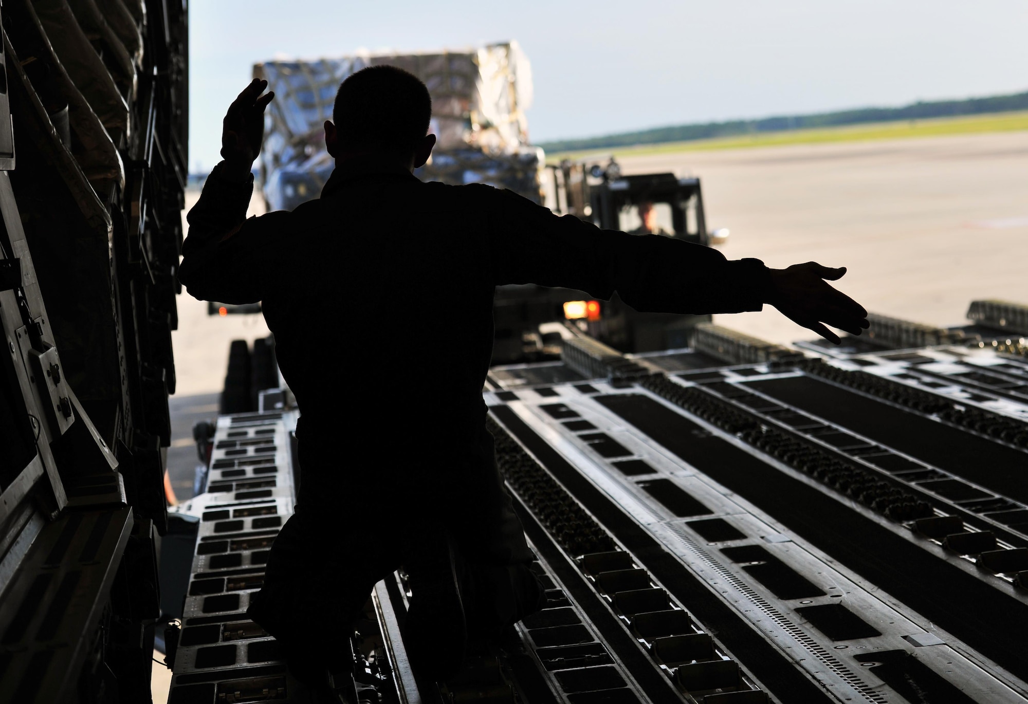 Tech. Sgt. Eric Blevins, 316th Airlift Squadron loadmaster, marshals a cargo loader toward a C-17 Globemaster, May 27, 2015, at Hurlburt Field, Fla. Members of the 823rd RED HORSE deployed to Honduras in support of NEW HORIZONS 2015, an annual event conducted to train military civil engineers and medical professionals to deploy and conduct joint operations. (U.S. Air Force photo by Airman 1st Class Ryan Conroy/Released)
