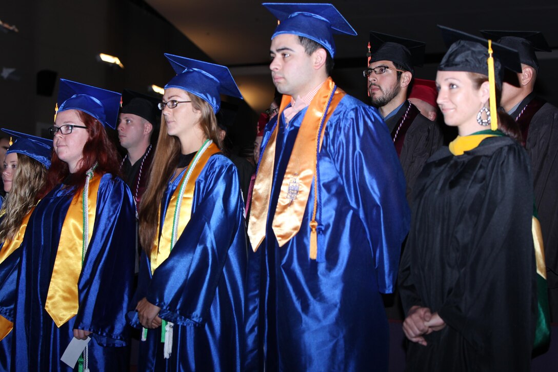 Graduating students stand while fellow graduates receive diplomas during the 40th annual graduation recognition ceremony at Marine Corps Air Station Cherry Point, North Carolina, May 28, 2015. The Ceremony was held to honor students’ extraordinary accomplishments as they completed degrees in their fields of study.
