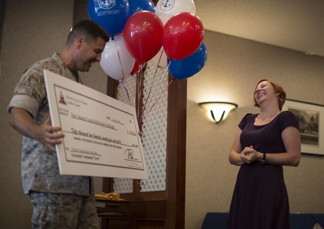 Col. Robert B. Boucher, commanding officer of MCAS Iwakuni, presents a $50,275 check to Deanna O’neal, director of the NMCRS Iwakuni, during an award ceremony inside of Talbots for unit representatives of the Active Duty Fund Drive, May 29, 2015. Donations made to the ADFD go right back into the pockets of Marines and sailors in cases of emergencies. The ADFD runs annually, March through April, by request of the Commandant of the Marine Corps and the Chief of Naval Operations and in the last four years the total amount of money donated increased every year.