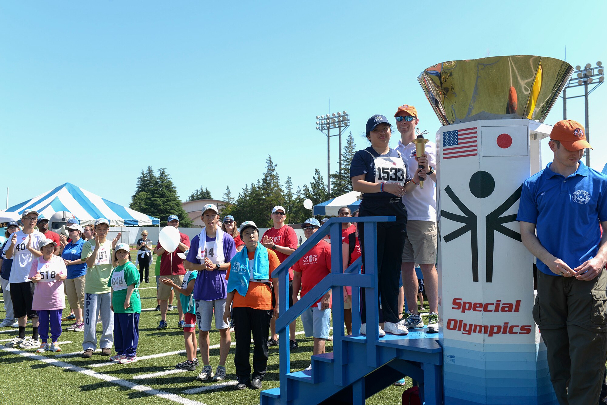 Master Sgt. Josh Hodgen, 374th Medical Group first sergeant, lights the torch with a participant at the 36th  annual Kanto Plains Special Olympics opening ceremony at Yokota Air Base, Japan, May 30, 2015. Athletes in the KPSO ranged from children to adults and included both Japanese and American participants. (U.S. Air Force photo by Airman 1st Class Elizabeth Baker/Released)