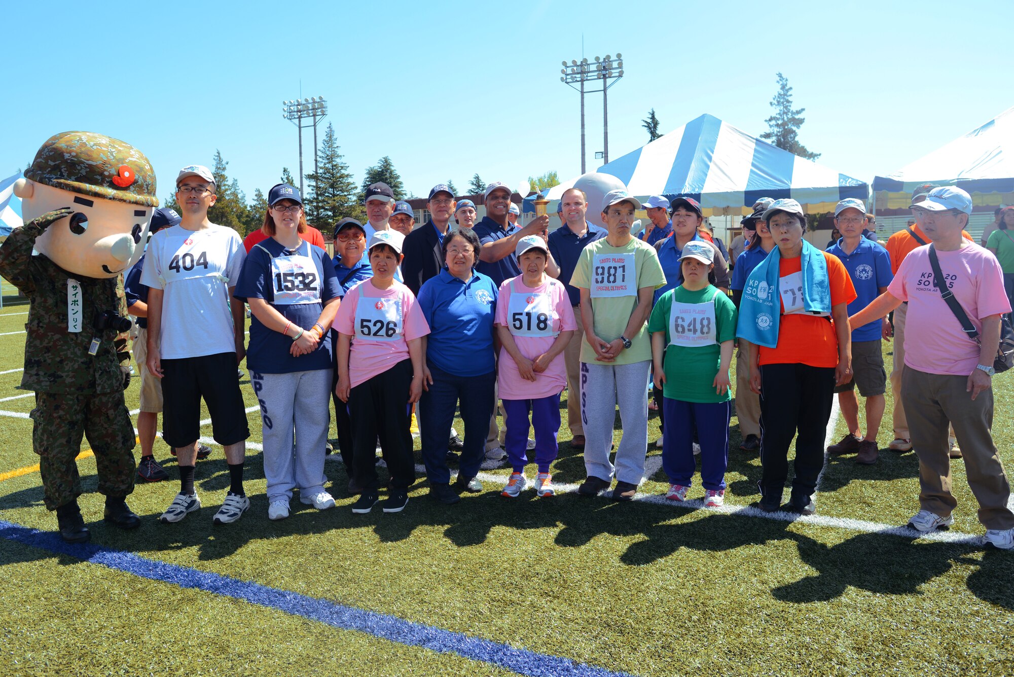 374th Medical Group vice commander Col. Trent Tate, and 374th Airlift Wing Command Chief Master Sgt. Paul Elliot pose with Kanto Plain Special Olympics competitors May 30, 2015, at Yokota Air Base, Japan. 159 disabled children and adults from nine schools throughout the Kanto Plain region competed in various sports events throughout the day. (U.S. Air Force photo by Airman 1st Class Delano Scott/Released)