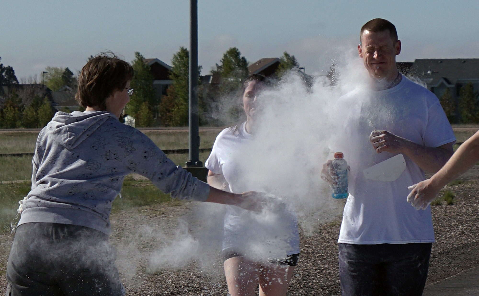 Airman 1st Class Lelaini Rinker, 90th Missile Maintenance Squadron, blasts Airman 1st Class Thomas Gustafson and Siobhan Lynch, 90th Medical Operations Squadron, with white corn starch during the Air Force Sergeant’s Association 5-kilometer Color Run May 30, 2015. Bystanders pelted runners with different color powders as they ran the course. (U.S. Air Force photo by Airman 1st Class Brandon Valle)