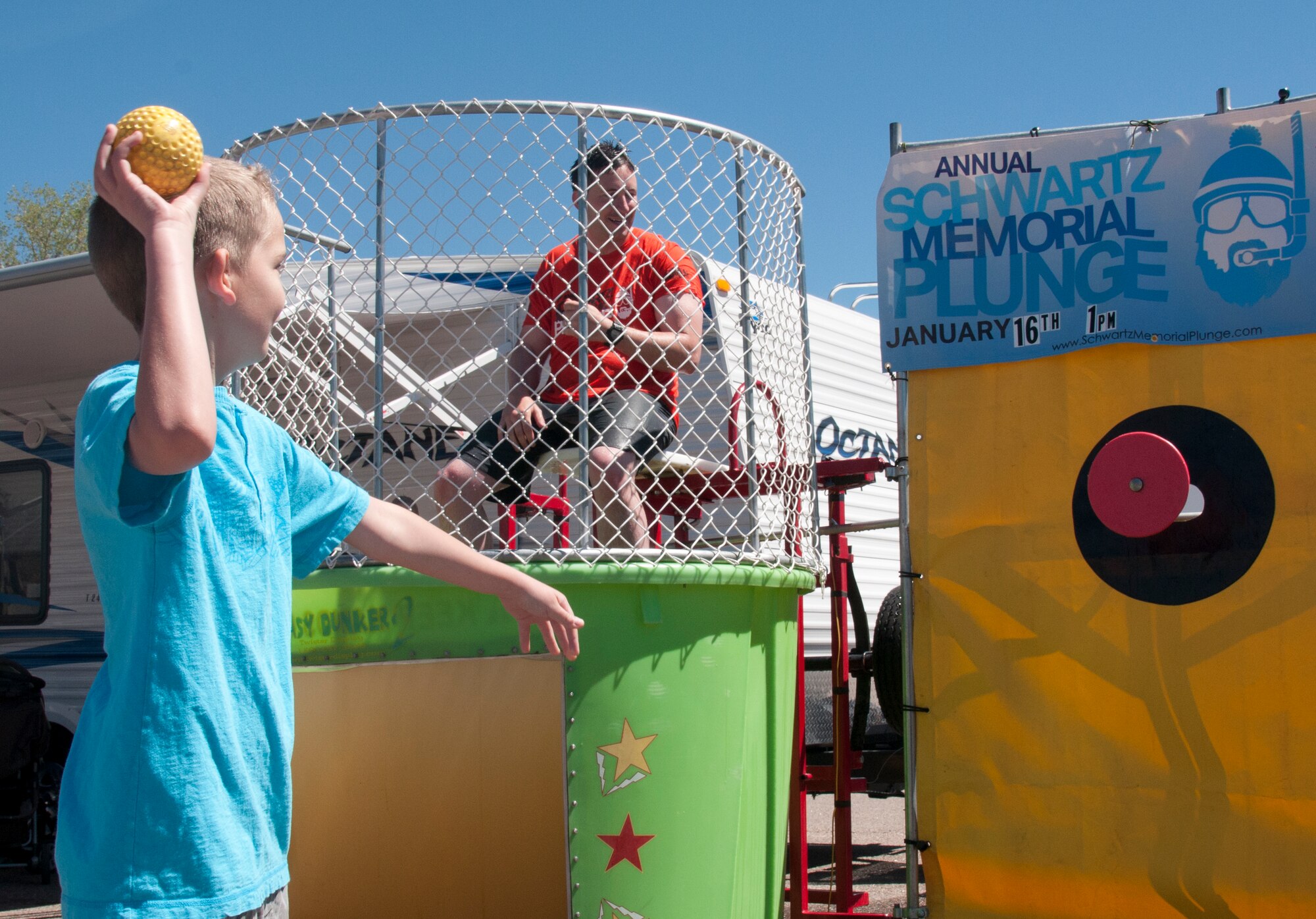 The 10-year-old son of Senior Master Sgt. Donald Deming, 90th Civil Engineer Squadron Explosive Ordnance Disposal superintendent, attempts to knock down Staff Sgt. Daniel Nickelson, 90th CES EOD team member, during the Military May event near the Cheyenne, Wyo., Capitol building, May 30, 2015. The family-friendly atmosphere was enhanced by the carnival-like displays. (U.S. Air Force photo by Airman 1st Class Malcolm Mayfield)