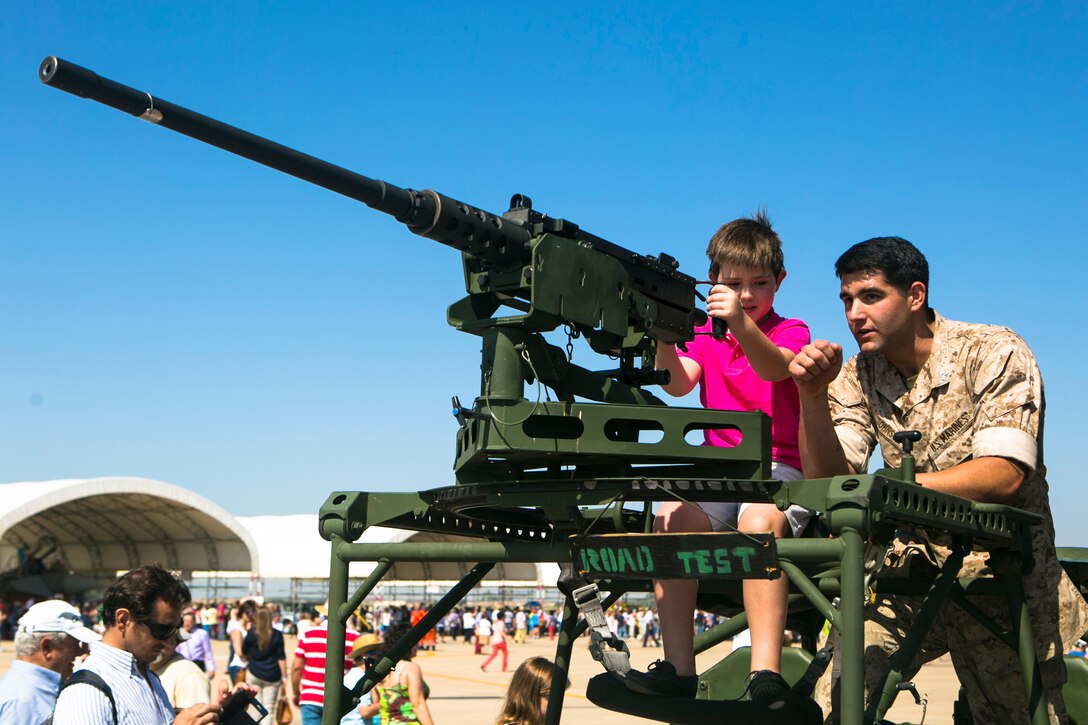 A U.S. Marine shows an attendee of the 75th Anniversary celebration of Moron Air Base how to use a .50-caliber machine gun on Moron Air Base, Spain, May 31, 2015. The Marines demonstrated various weapons systems for visitors, who were able to tour a variety of U.S. and Spanish military displays. The Marines are assigned to the Special-Purpose Marine Air-Ground Task Force Crisis Response-Africa. 