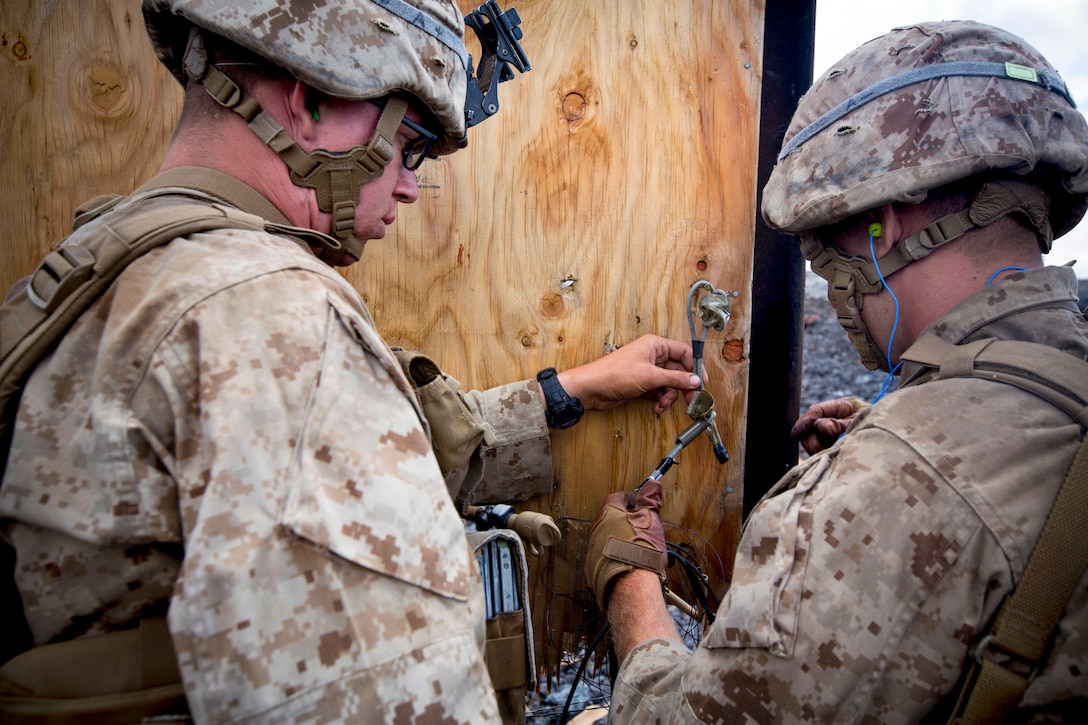 Marines place a donut charge on a makeshift door handle during
