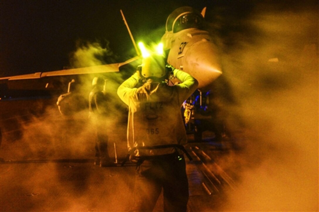 A U.S. seaman directs an E/A-18G Growler to the catapult on the flight deck of the aircraft carrier USS Theodore Roosevelt in the U.S. 5th fleet area of operations, May 28, 2015. The Theodore Roosevelt is supporting Operation Inherent Resolve, which includes strike operations in Iraq and Syria as directed.