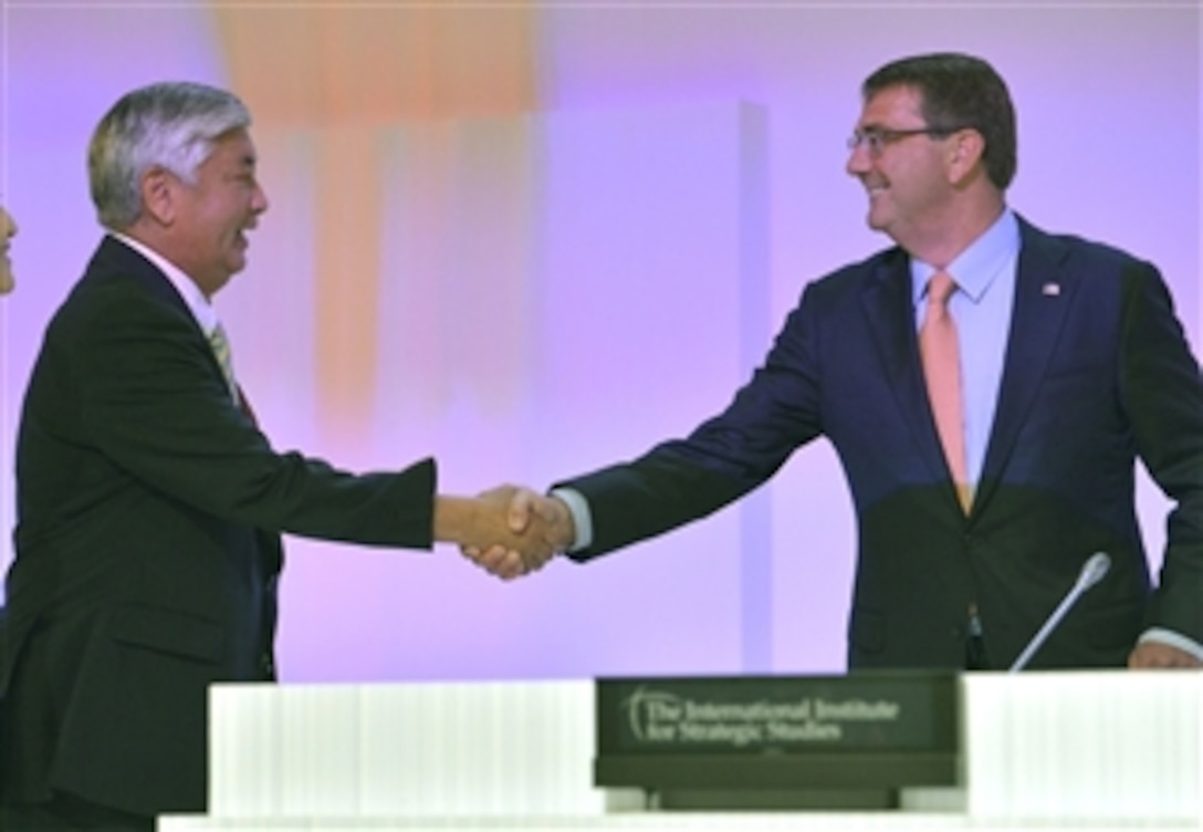 Japanese Defense Minister Gen Nakatani, left, walks on stage to greet U.S. Defense Secretary Ash Carter before Carter's opening plenary speech at the Shangri-La Dialogue in Singapore, May 30, 2015.