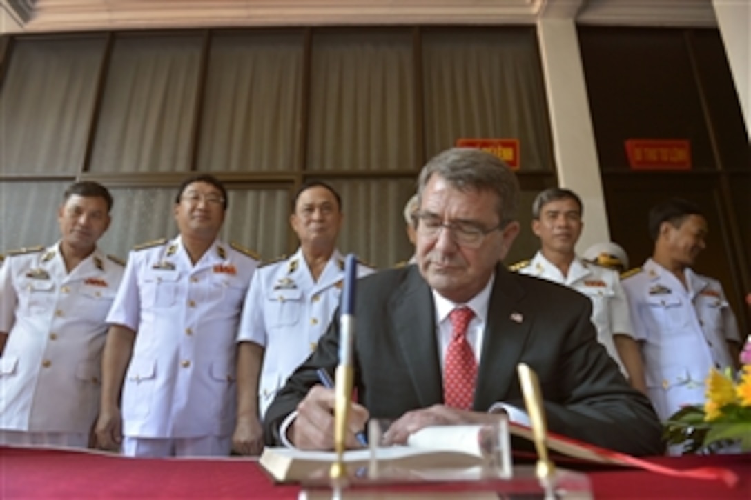 Vietnamese naval officers stand in a row behind Defense Secretary Ash Carter as he signs the guestbook after meeting with Vice Minister of Defense and Commander of the People's Navy of Vietnam, Adm. Nguyen Van Hien in Vietnam, May 31, 2015.