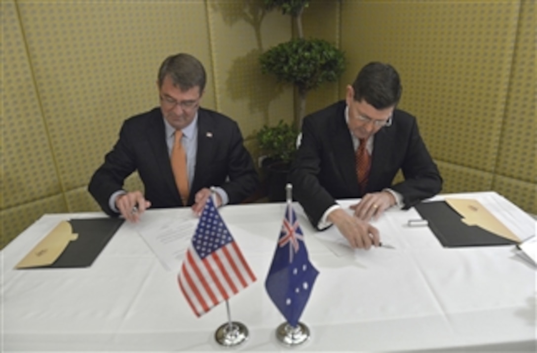 U.S. Defense Secretary Ash Carter, left, and Australia's Minister of Defense Kevin Andrews sign a Memorandum of Understanding on Agreed Facilities and Areas while attending the Shangri-La Dialogue in Singapore, May 30, 2015.