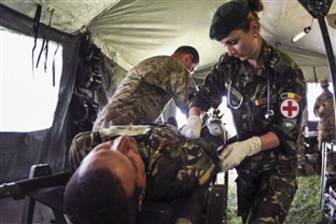 U.S. Army Sgt. Christopher Tupper, back left, and Sgt. Ramona Nicolau with Romania's land forces unstrap a simulated patient who was secured to a litter during their evacuation training at the Cincu Training Area, Romania, May 30, 2015. 