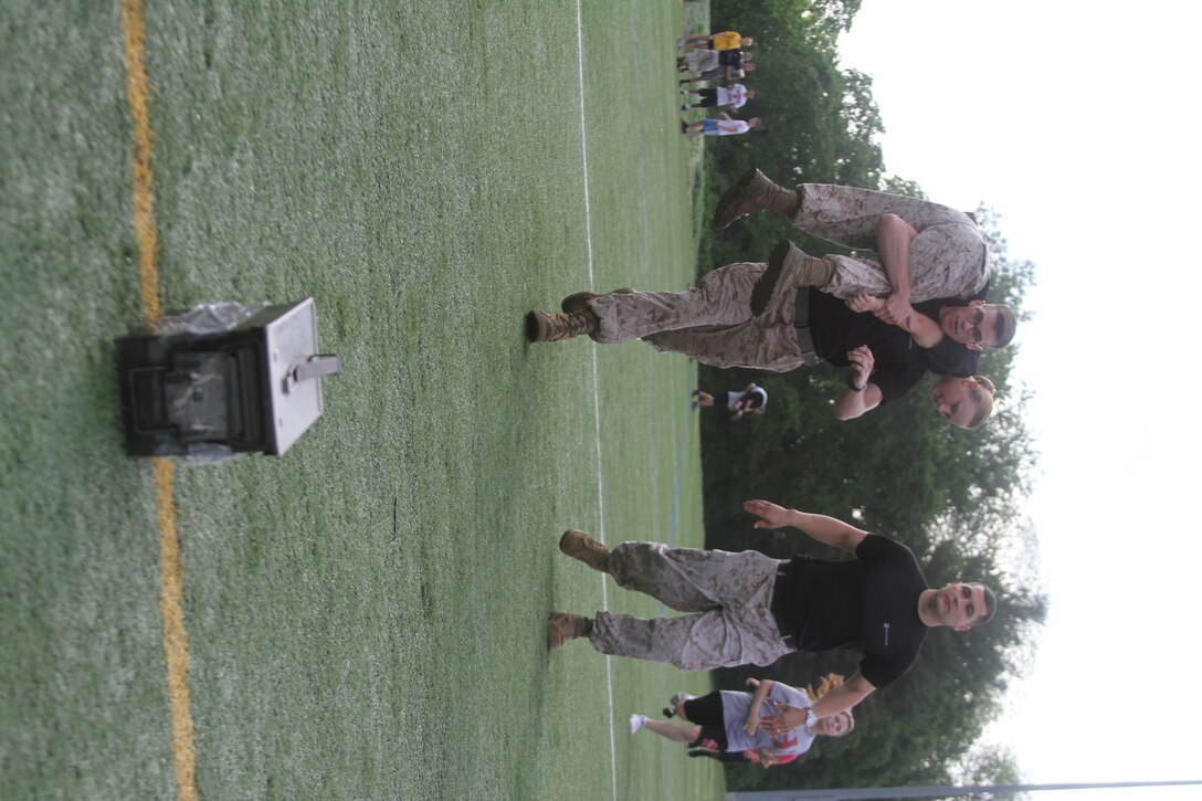 Marines of Recruiting Sub-station Leesburg demonstrate how to go through a customized team relay race May 19, 2015, at Herndon High School in Herndon, Virginia. Throughout the day, the Marines put multiple classes of students through a series of physically demanding exercises including ammunition can lifts, squad pushups and relay races. (U.S. Marine Corps photo by Sgt. Anthony Kirby/Released)