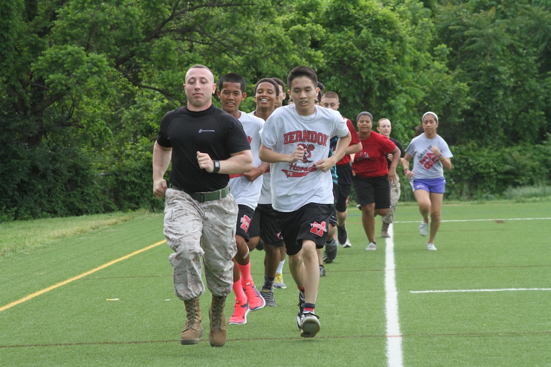 U.S. Marine Corps Sgt. Michael A. DeCamilla Jr., recruiter for Recruiting Sub-station Leesburg and native of Rochester, New York, sets the pace for Herndon High School students May 19, 2015, in Herndon, Virginia. Throughout the day, DeCamilla and other Marines multiple of students through a series of physically demanding exercises including ammunition can lifts, squad pushups and relay races. (U.S. Marine Corps photo by Sgt. Anthony Kirby/Released)