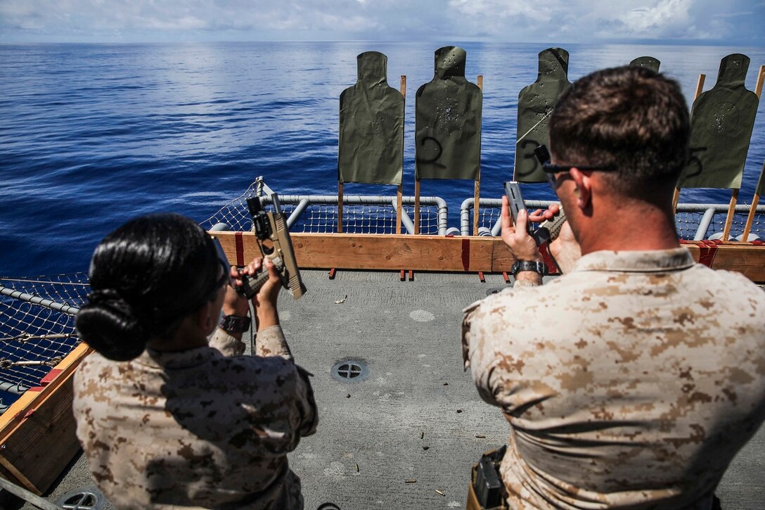 Gunnery Sgt. Robert Turek, right, teaches Midshipman Jessica Gonzalez how to operate the 1911 pistol aboard the USS Essex (LHD 2) at sea in the Pacific Ocean, June 1, 2015. Turek is with the 15th Marine Expeditionary Unit’s Maritime Raid Force and Gonzalez is a midshipman from San Antonio, Texas. Gonzalez is aboard the USS Essex during summer training for the Reserve Officers’ Training Corps. (U.S. Marine Corps photo by Cpl. Anna Albrecht/Released)