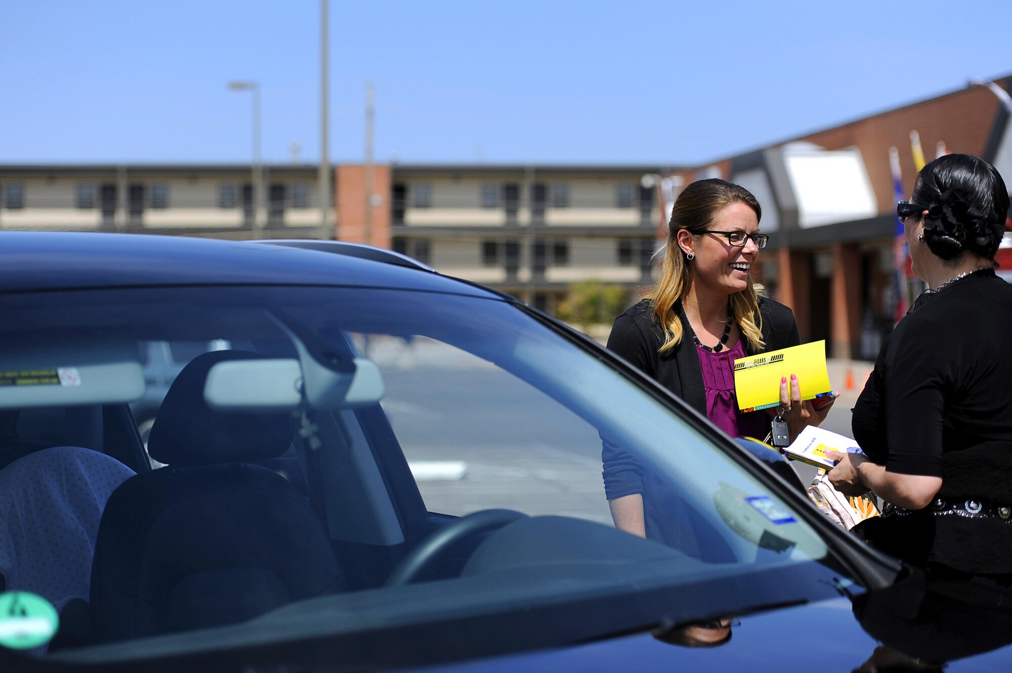 Cecilia Diaz, right, 17th Medical Group Family Advocacy Program manager, informs Michelle Brooks, 315th Training Squadron contractor, about the dangers of leaving children in unattended cars during a social experiment in the commissary parking lot on Goodfellow Air Force Base, Texas, May 29, 2015. The Family Advocacy Program staged an infant decoy, left in an unattended vehicle, projecting a crying baby audio track to observe how people would respond. (U.S. Air Force photo by Tech. Sgt. Austin Knox/Released)