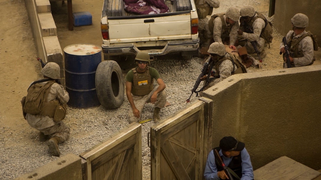 Marines with 1st Battalion, 10th Marine Regiment, take cover after rounds are fired, by enemy role-players during Infantry Immersion Training aboard Camp Lejeune, N.C., May 29, 2015.  The immersion center is an indoor Military Operation on Urban Terrain environment that allows Marines to go through a life-like village and encounter role-players to better sharpen their MOUT skills.  (U.S. Marine Corps Photo by Cpl. Michael Dye/Released) 