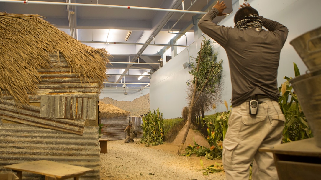 A Marine with 1st Battalion, 10th Marine Regiment, gives orders to a role-player, who is acting as the enemy, during Infantry Immersion Training aboard Camp Lejeune, N.C., May 29, 2015. The immersion center is an indoor Military Operation on Urban Terrain environment that allows Marines to go through a life-like village and encounter role-players to better sharpen their MOUT skills.  (U.S. Marine Corps Photo by Cpl. Michael Dye/Released) 