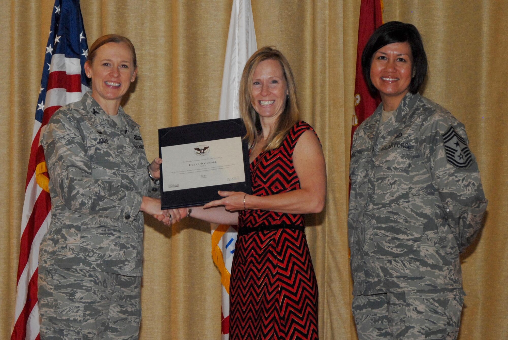 U. S. Air Force Col. Kimberlee P. Joos, 17th Training Wing Commander, and Chief Master Sgt. JoAnne S. Bass, 17th TRW Command Chief, present Debra L. Scougall, 17th Force Support Squadron Exceptional Family Member Program specialist and school liaison officer, a President’s Volunteer Service Award Gold Medal during a volunteer recognition event at the base theater on Goodfellow Air Force Base, Texas, June 1, 2015. Scougall received the award for volunteering 500 or more hours over the past year. (U.S. Air Force photo by Senior Airman Joshua Edwards/Released)