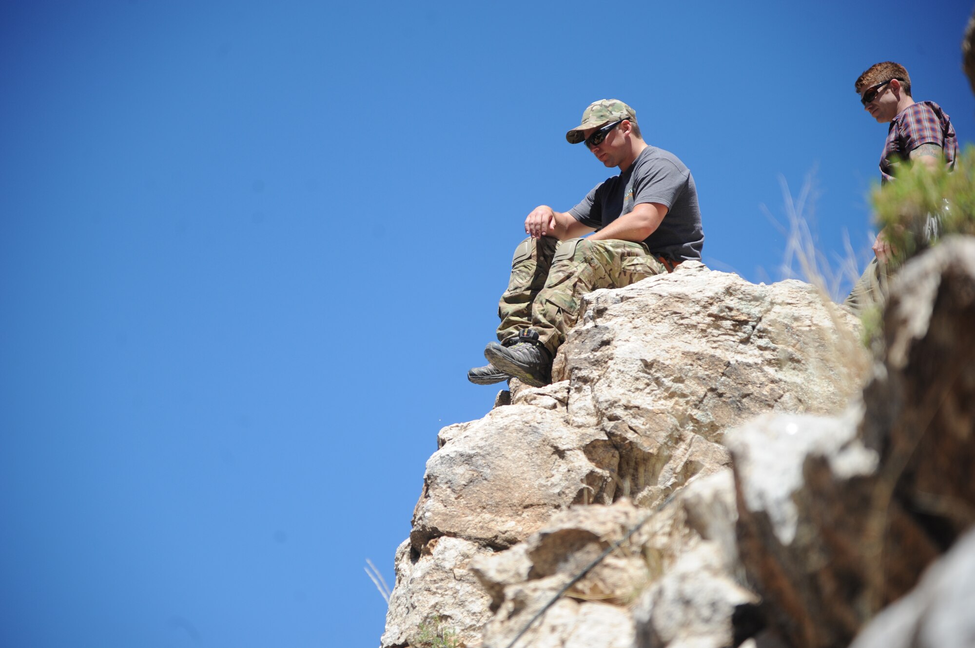 U.S. Air Force Senior Airman Miles Roberts, reserve pararescueman, observes a fellow pararescueman rappel during Angel Thunder 2015 high angle rescue training at Mount Lemmon, Ariz., June 1, 2015. During the training, U.S. Marines and U.S. Airmen practiced tying knots, anchoring ropes, rappelling down a cliffside unassisted, and returning to the initial elevation point. Angel Thunder is an Air Combat Command-sponsored personnel recovery exercise for combat air force, joint, allied and interagency participants. Roberts is assigned to the 304th Reserve Squadron at Portland Air National Guard Base, Ore. (U.S. Air Force photo by Senior Airman Betty R. Chevalier/Released)