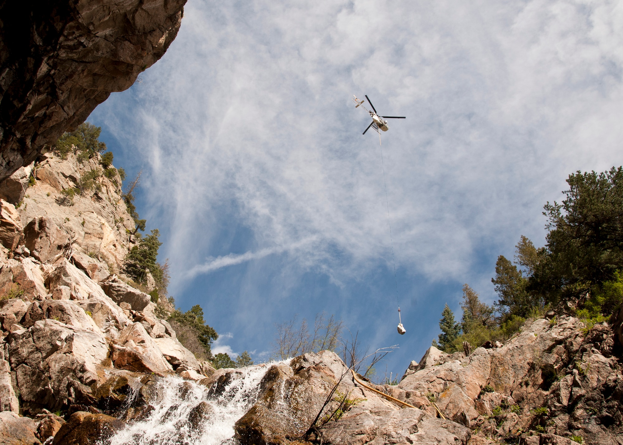 CHEYENNE MOUNTAIN AIR FORCE STATION, Colorado – A “Lama” helicopter designed for high elevation, lifts equipment in and out of the canyons where ring nets are to be installed, May, 28, 2015. The five ring nets are one of four steps in the mitigation process to reduce the damage of future landslides. The ring nets, 15-foot deep main catchment basin, a culvert down the mountain into the storm water system and infrastructure protection are being built as a result of landslides that struck the mountain Sept. 12, 2013, following torrential rain. (U.S. Air Force photo by Senior Airman Tiffany DeNault)
