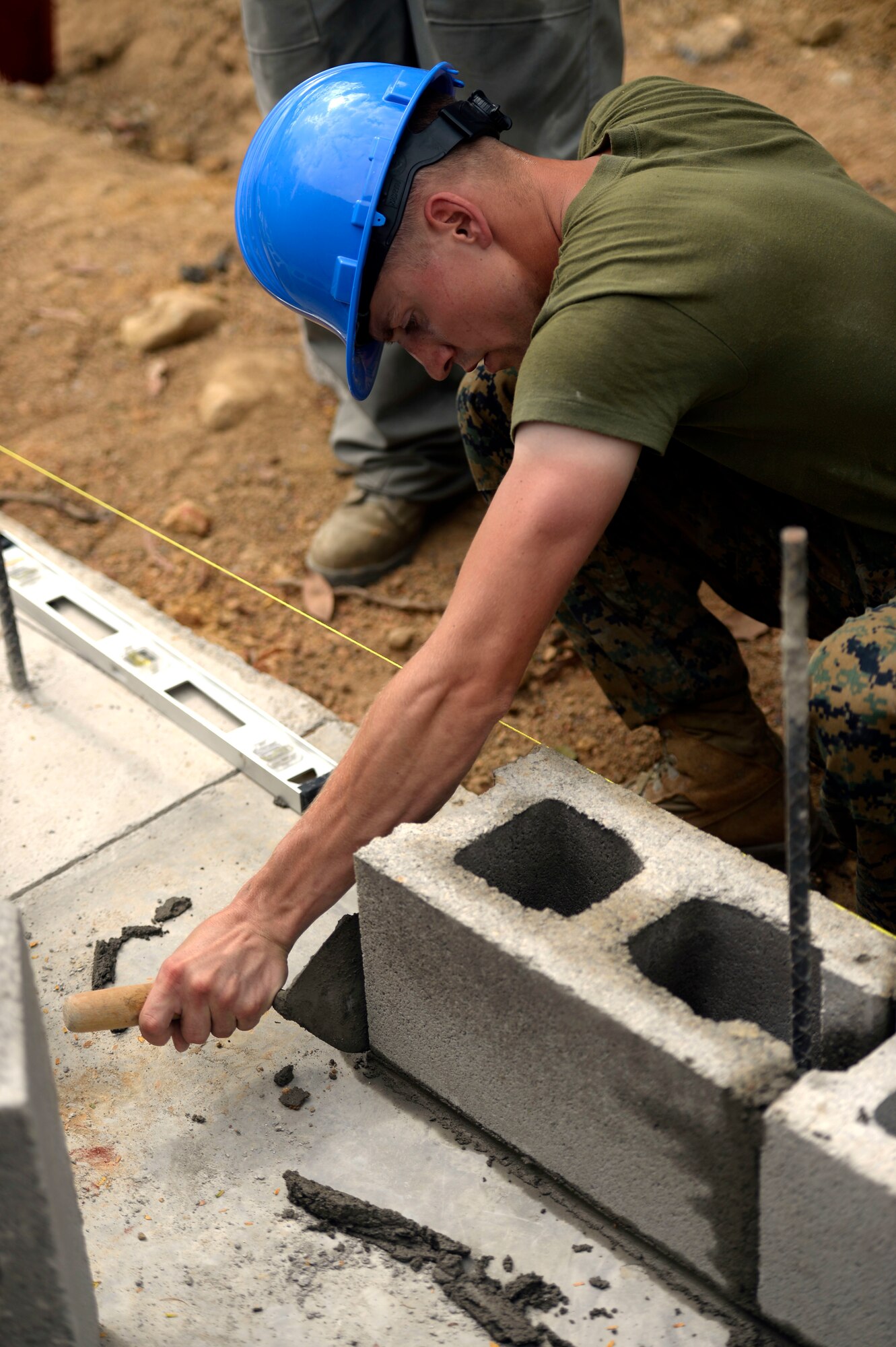 U.S. Marine Sgt. Caleb Rey, a combat engineer and Spring Hope, N.C., native with the 271st Marine Wing Support Squadron, 2nd Marine Air Wing, out of Marine Corps Air Station Cherry Point, N.C., cleans mortar from around a block in the first course of bricks being laid for the Gabriela Mistral primary school in Ocotoes Alto, June 1, 2015. The construction project is part of the New Horizons Honduras 2015 training exercise, an annual humanitarian exercise put on by U.S. Southern Command. New Horizons was launched in the 1980s and is an annual joint humanitarian assistance exercise that U.S. Southern Command conducts with a partner nation in Central America, South America or the Caribbean. The exercise improves joint training readiness of U.S. and partner nation civil engineers, medical professionals and support personnel through humanitarian assistance activities. (U.S. Air Force photo by Capt. David J. Murphy/Released)