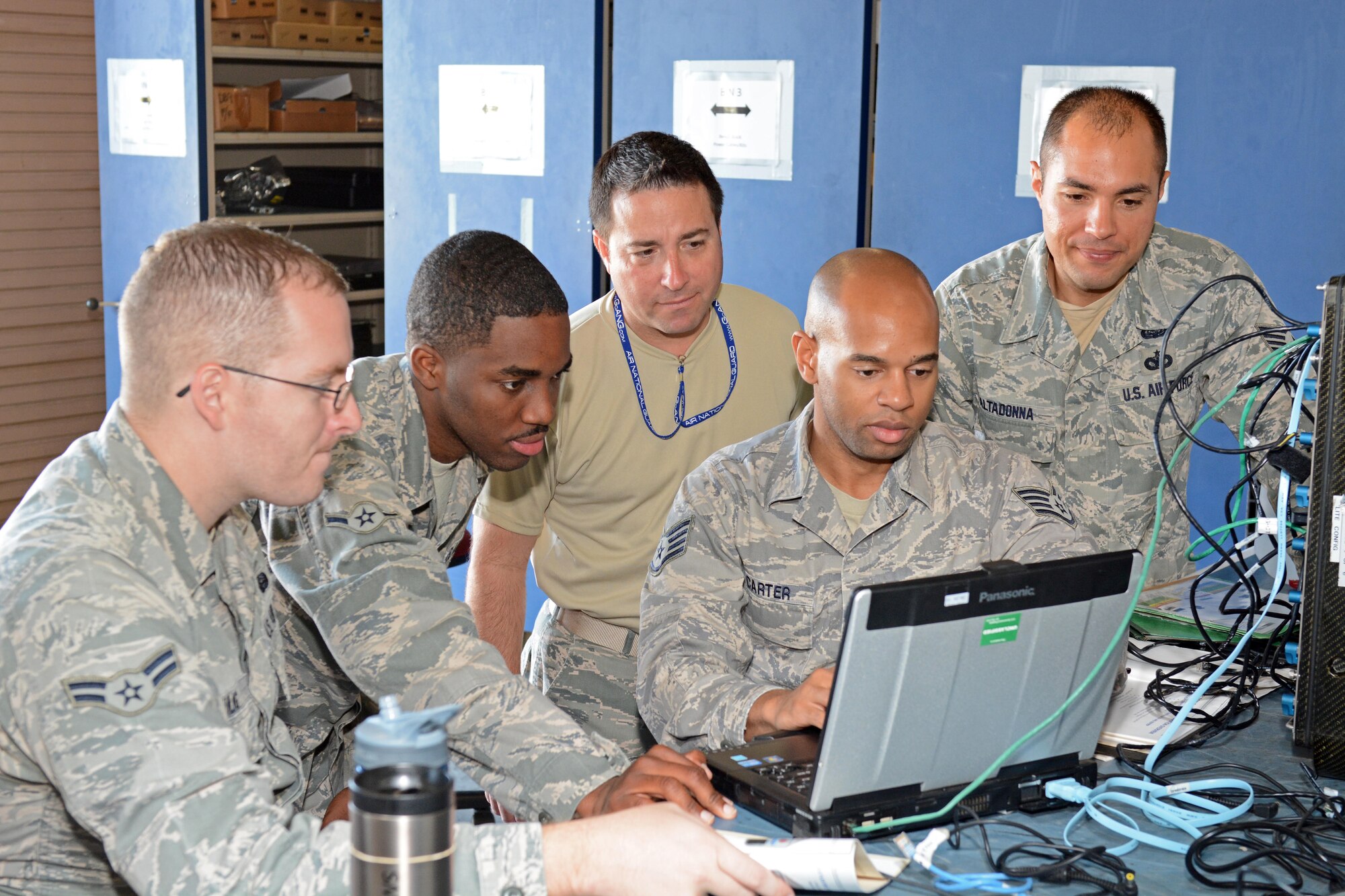 U.S. Air Force Staff Sgt. Darius Carter and Airman Tyler Kulig with the help from others in the 290th Joint Communications Support Squadron "B-Flight" troubleshoot the setup and configuration of a JBlox baseband equipment at MacDill Air Force Base, Tampa Florida, May 3, 2015. The JBlox baseband equipment is used to connect phones and computers to satellite systems. (U.S. Air Force photo by SSgt Troy Anderson/Released)