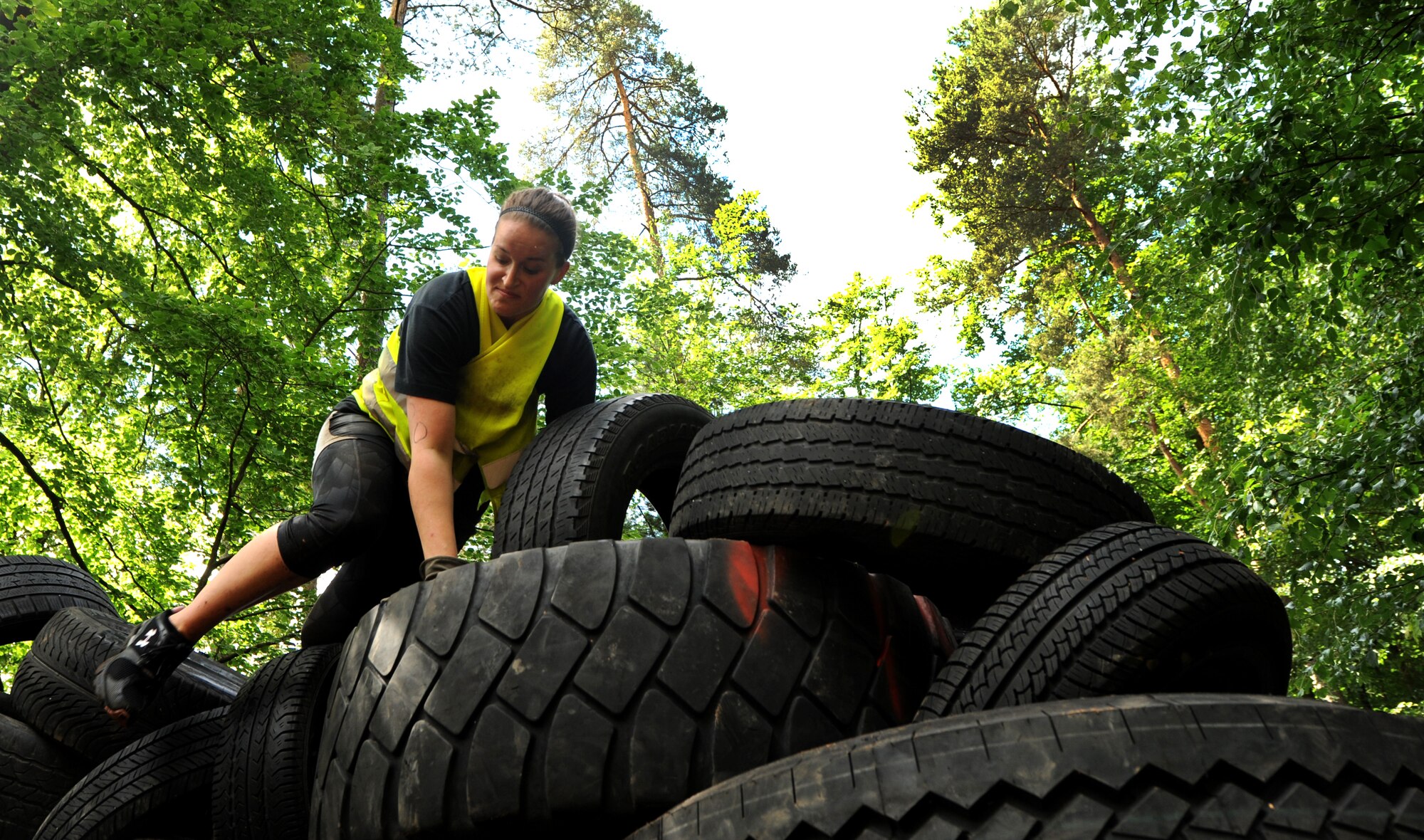 A member of team "Dorm Rangers" climbs a tire wall during the Mudless Mudder event June 2, 2015, at Ramstein Air Base, Germany. Mudless Mudder was part of the 86th Airlift Wing's Resiliency Day, which gave participants the opportunity to spend time with others and build working relationships. (U.S. Air Force photo/Staff Sgt. Sharida Jackson)