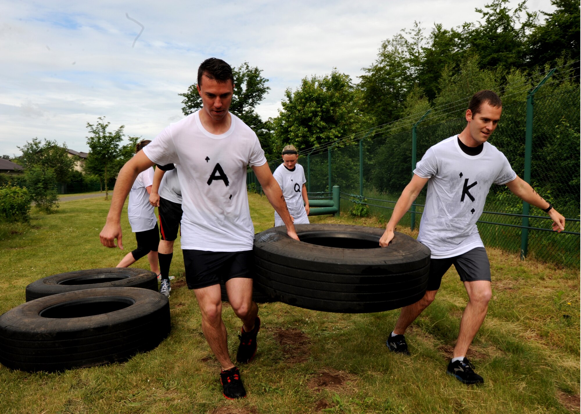 Members of team "Royal Flush" perform a tire carry during the Mudless Mudder event June 2, 2015, at Ramstein Air Base, Germany. Mudless Mudder was part of the 86th Airlift Wing's Resiliency Day, which gave members an opportunity to strengthen team building. (U.S. Air Force photo/Staff Sgt. Sharida Jackson)