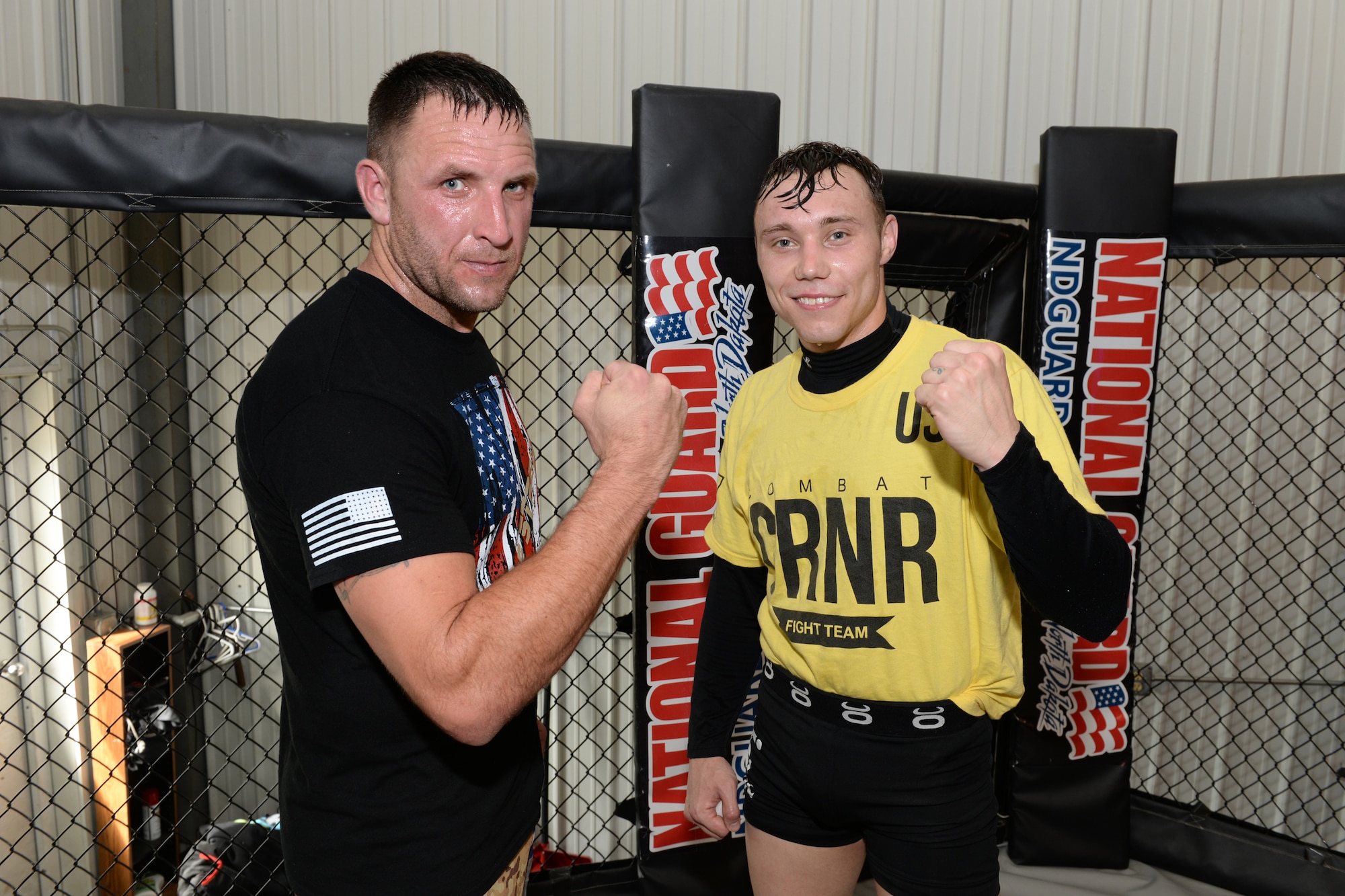 Senior Airman Michael Bullen, right, and Tech. Sgt. Gemenie Strehlow, both of the 119th Security Forces Squadron pose for a photo in the mixed martial arts cage at a Fargo, North Dakota, gym, May 8, 2015. The Airmen are training at the gym to enhance their fitness and skills to be better prepared in their career field for potential threats on duty. Bullen is scheduled for a competitive mixed martial arts match May 16 in Detroit Lakes, Minnesota. (U.S. Air National Guard photo by Senior Master Sgt. David H. Lipp/Released)