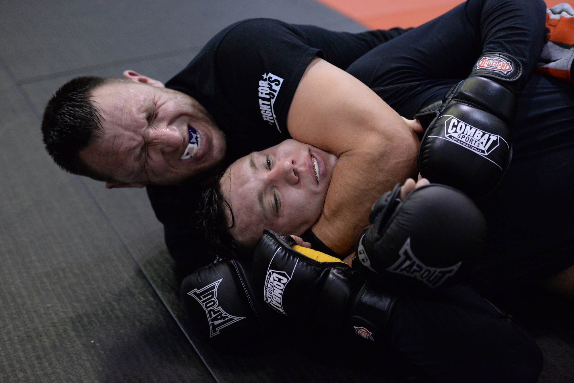 Tech. Sgt. Gemenie Strehlow works for a choke hold on Senior Airman Michael Bullen, both of the 119th Security Forces Squadron, as they practice mixed martial arts techniques while training at a Fargo, North Dakota gym. The Airmen are training at the gym to enhance their fitness and skills to be better prepared in their career field for potential threats on duty.  (U.S. Air National Guard photo by Senior Master Sgt. David H. Lipp/Released)