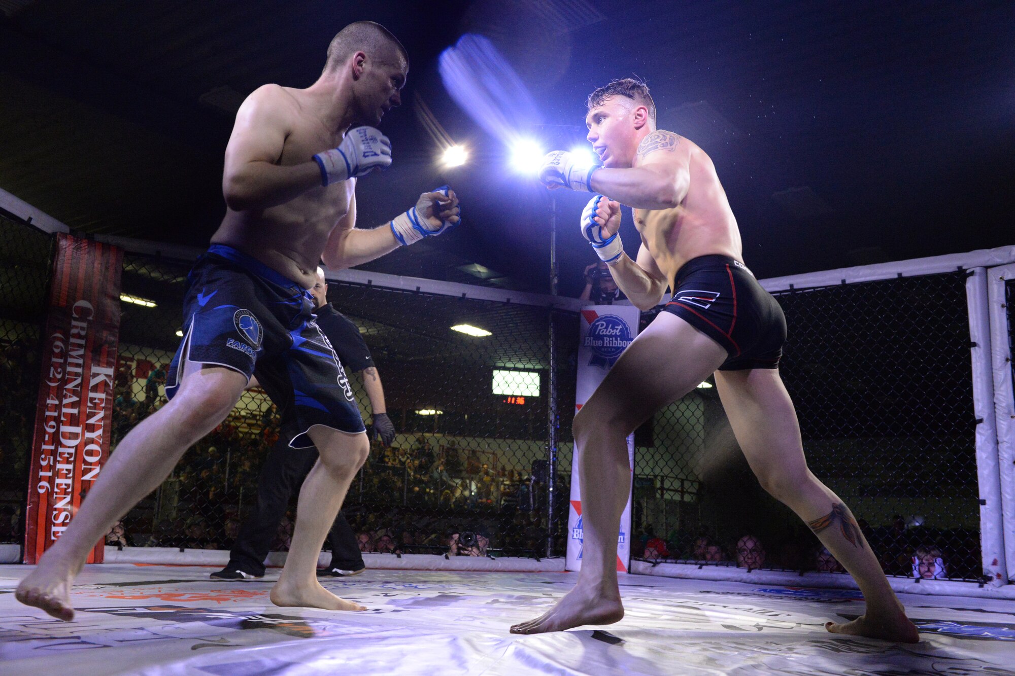 Senior Airman Michael Bullen, of the 119th Security Forces Squadron, right, faces off with his opponent during his mixed martial arts fight in the center stage fighting cage at the Freeman Arena, Detroit Lakes, Minnesota, May 16, 2015. The security forces Airman uses mixed martial arts training and fighting to enhance his fitness and skills to be better prepared in his career field and to be better prepared for potential threats on duty.  (U.S. Air National Guard photo by Senior Master Sgt. David H. Lipp/Released)