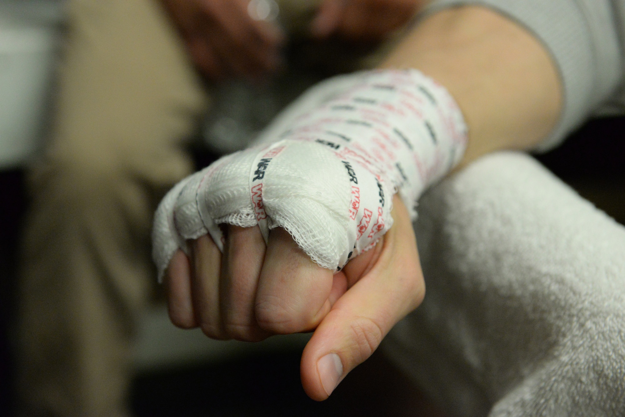 Senior Airman Michael Bullen, of the 119th Security Forces Squadron, makes a fist after his hand is wrapped prior to putting on his fighting gloves, as he prepares for a mixed martial arts fight May 16, 2015, the Freeman Arena, Detroit Lakes, Minnesota. The security forces Airman uses mixed martial arts training and fighting to enhance his fitness and skills to be better prepared in his career field and to be better prepared for potential threats on duty.  (U.S. Air National Guard photo by Senior Master Sgt. David H. Lipp/Released)