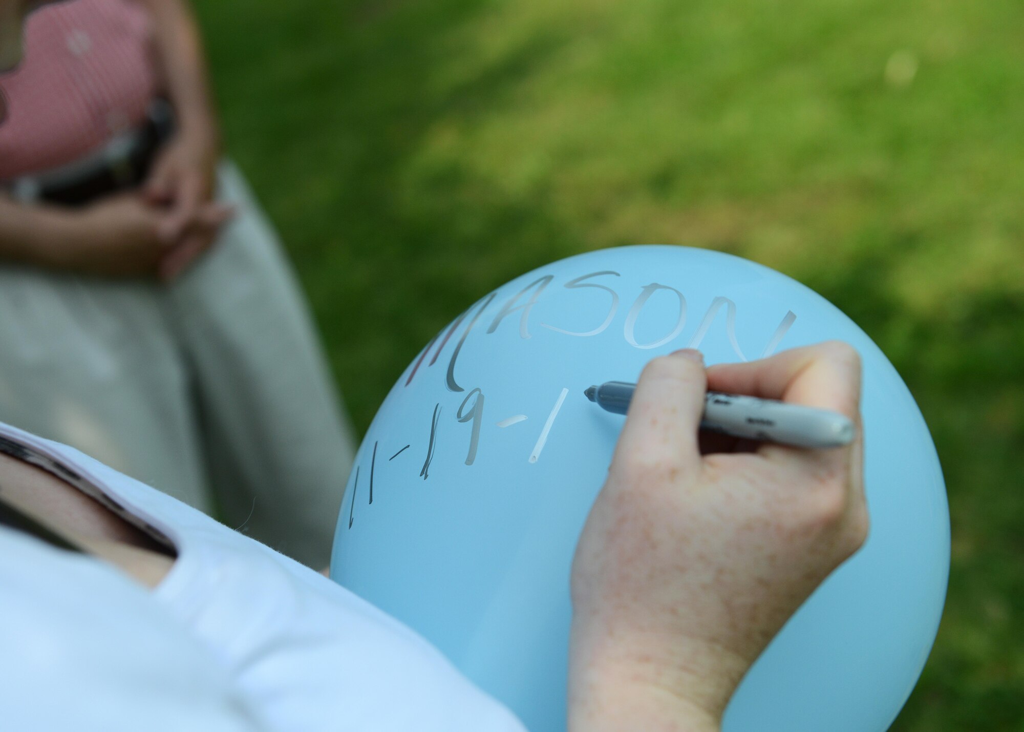 Brooke El-Attrache writes the name of her stillborn nephew, Mason, and the date he passed away, on a balloon, during the Airborne Angels’ balloon release event, May 30, 2015, at the park in San Quirino, Italy. El-Attrache, the president and founder of the local, non-profit organization, started the group in 2014 to help link people who have suffered the tragic loss of an infant or small child. (U.S. Air Force photo by Airman 1st Class Deana Heitzman/Released)