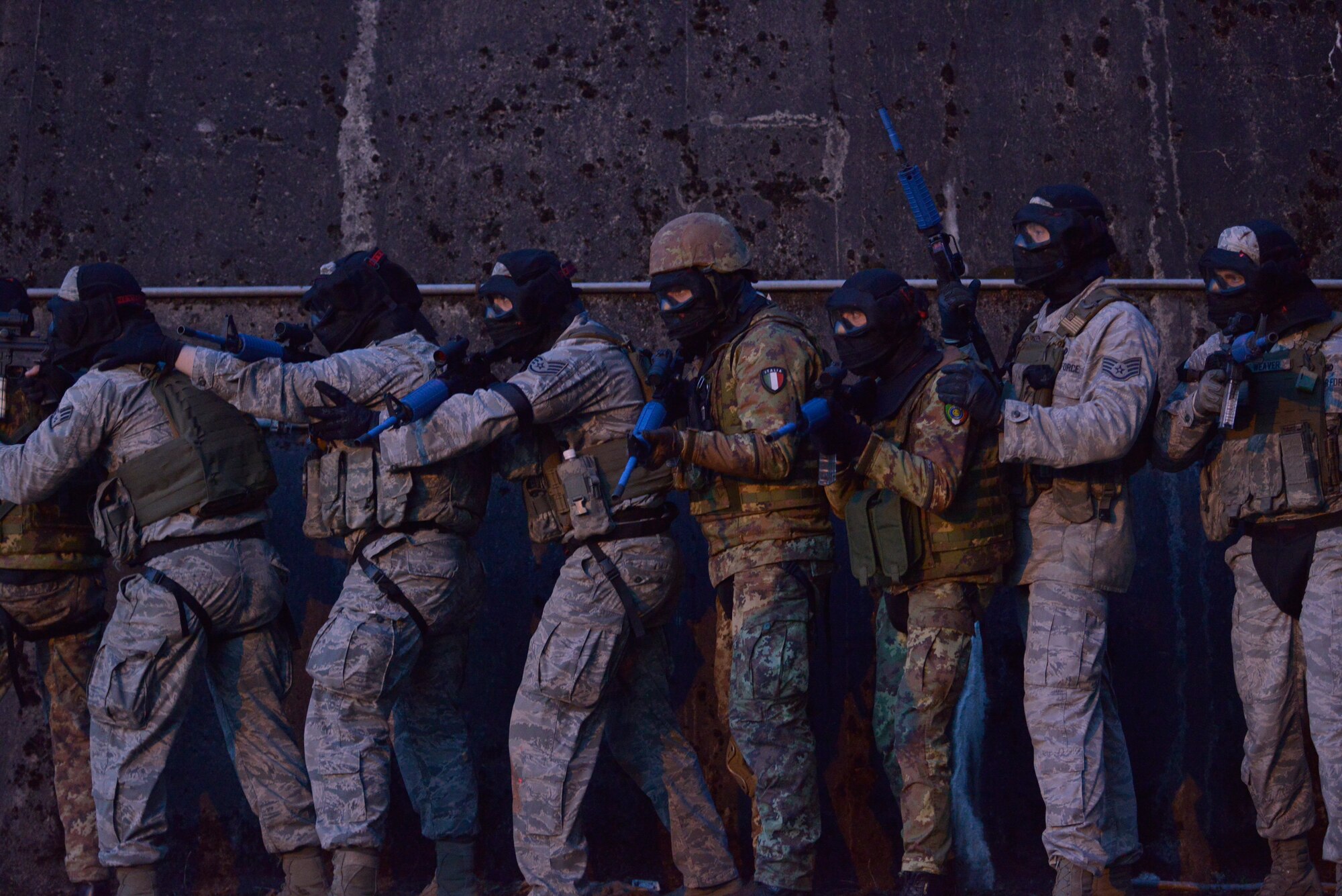 U.S. Airmen and Italian soldiers position themselves alongside a training hangar before breaching and clearing it during Battlefield Leaders Assaulter Course, Integrated Combat Essentials May 30, 2015, at Ramstein Air Base, Germany.  BLAC ICE brings together security forces members from Belgium, Germany, Netherlands and Italy with U.S. Air Force security forces members to promote a wider training standard among allied nations. (U.S. Air Force photo by Airman 1st Class Lane T. Plummer/Released)