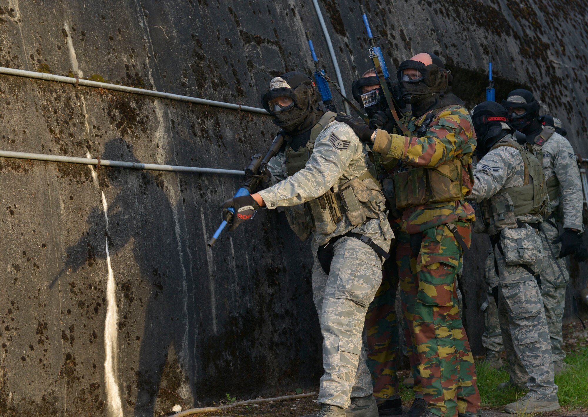 A group of U.S. Airmen and German soldiers take position beside a training hangar awaiting orders to breach and enter it during Battlefield Leaders Assaulter Course, Integrated Combat Essentials May 30, 2015, at Ramstein Air Base, Germany. The BLAC ICE training brings together U.S. Air Force security forces members with Belgium, Germany, the Netherlands and Italy security forces to train on advanced tactics, as well as set a standard fighting technique among allied countries.  (U.S. Air Force photo by Airman 1st Class Lane T. Plummer/Released)