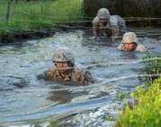 Marines with Electronics Maintenance Company, 2nd Maintenance Battalion, low-crawl through water and underneath barbed wire during the endurance course at the Battle Skills Training School aboard Camp Lejeune, N.C., May 29, 2015. ELMACO hiked approximately two miles to the school and then conducted the course to build camaraderie and say farewell to their commanding officer, Maj. Brian L. White. (U. S. Marine Corps photo by Cpl. Shawn Valosin)