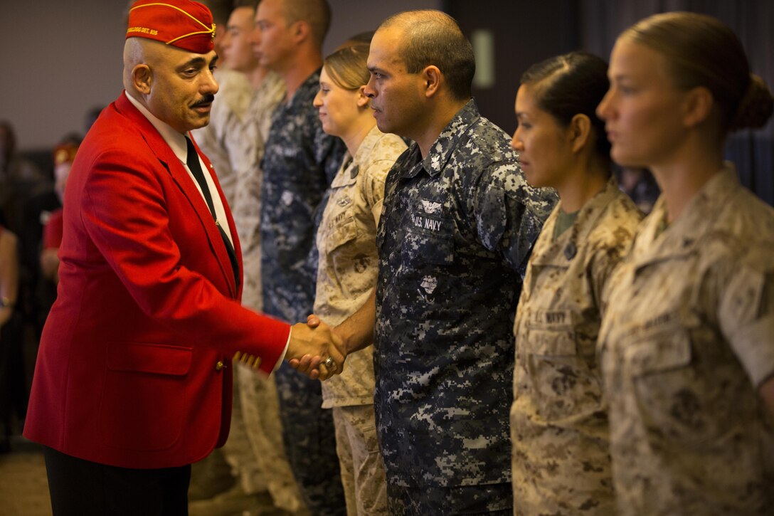 A representative with the Marine Corps League congratulates Marines and Sailors with Marine Corps Air Station Miramar and 3rd Marine Aircraft Wing during a Noncommissioned Officer, Marine and Sailors of the Quarter awards ceremony aboard the air station, June 2. Representatives from different organizations, such as the Marine Corps League, showed their support with a variety of gifts for the Marines and Sailors awarded at the ceremony. The Noncommissioned Officer, Marine and Sailors of the Quarter awards ceremony is held to honor those service members that have been recognized for their outstanding performance.
