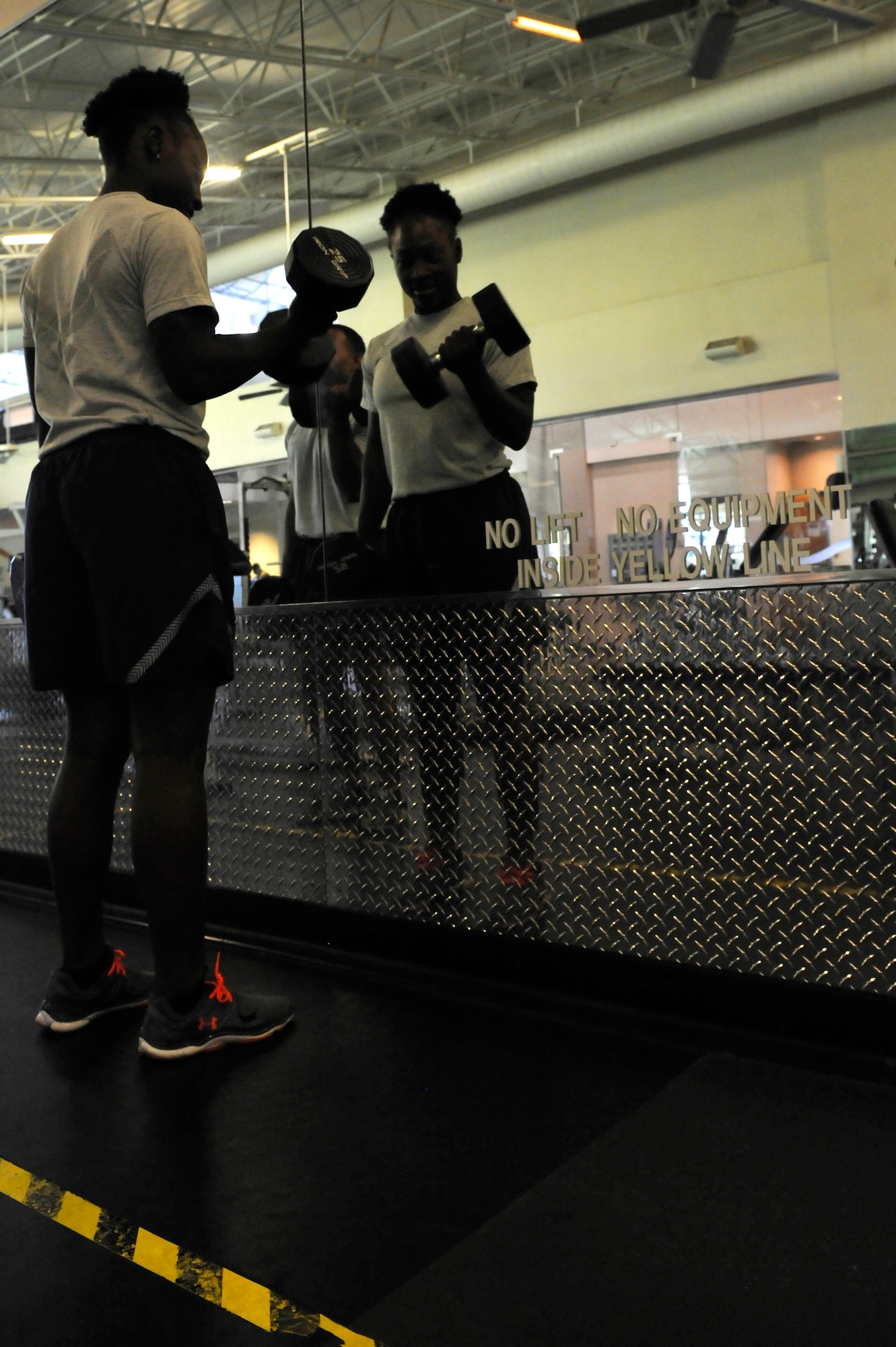 U.S. Air Force Tech. Sgt. Jessica Covington, 633rd Force Support Squadron fitness center non-commissioned officer in charge, lifts weights inside the yellow line at the Shellbank Fitness Center on Langley Air Force Base, Va., June 1, 2015. Performing exercises inside the yellow line can cause damage to the mirrors when using weights improperly.  (U.S. Air Force photo by Senior Airman Breonna Veal/Released)