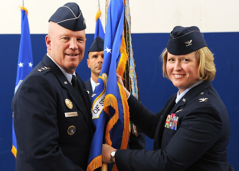 U.S. Air Force Lt. Gen. John W. "Jay" Raymond, commander, 14th Air Force (Air Forces Strategic) and Joint Functional Component Command for Space, passes the guidon to Col. DeAnna M. Burt, as she assumes command of the 50th Space Wing, during the change-of-command ceremony Friday at Schriever Air Force Base, Colo. As wing commander, Burt will be responsible for more than 4,200 military, Department of Defense civilians and contractor personnel serving at 14 operating locations worldwide and operating 69 surveillance, navigation and timing, space situational awareness and communication satellites valued at more than $66 billion.(U.S. Air Force Photo/Dennis Rogers)