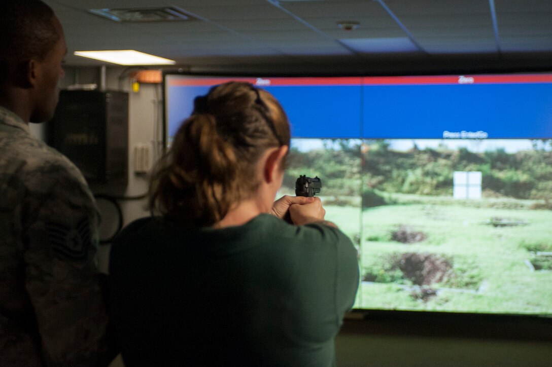 U.S. Air Force Tech. Sgt. Franklin Mosley, 633rd Security Forces Squadron, instructs Dina Persico, Kecoughtan High School teacher, on proper shooting procedures using a range simulator at Langley Air Force Base, Va., May 29, 2015. Persico and more than 100 students from Hampton Roads area high schools toured Langley to learn about the Air Force mission and the installation Airman’s impact. (U.S. Air Force photo by Senior Airman R. Alex Durbin/Released)