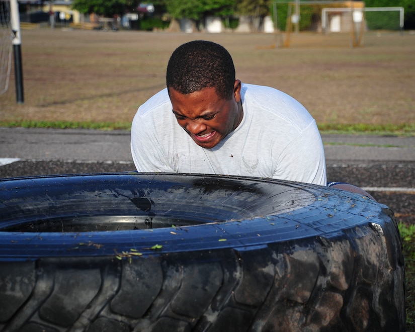 Capt. Jerrel Scriven, Joint Task Force-Bravo director of protocol, braces to flip a tire during a “Sgt. Maj. PT” session June 03, 2015, at Soto Cano Air Base, Honduras. These sessions, led by Command Sgt. Maj. Nelson Callahan, JFT-B Command Sgt. Maj., afford service members the chance to strengthen themselves physically and as a team.