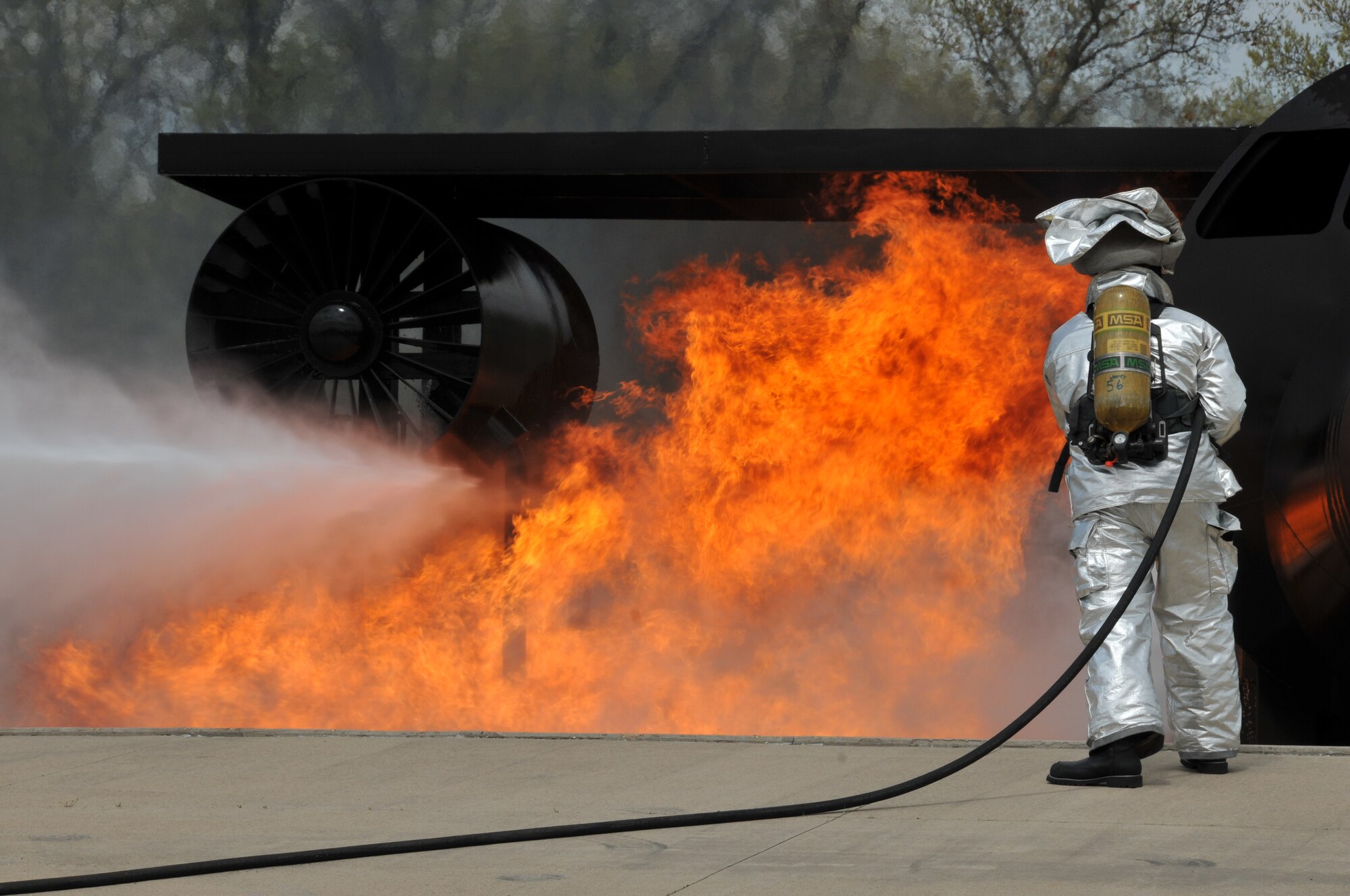A firefighter from the 114th Civil Engineer Squadron puts out a simulated aircraft engine burn as part of their live fire training at Volk Field, Wisc. May 6, 2015. The firefighters travel to Volk Field each year to hone their basic skills and to train on a simulated burning aircraft. (National Guard photo by Senior Airman Duane Duimstra/Released)
