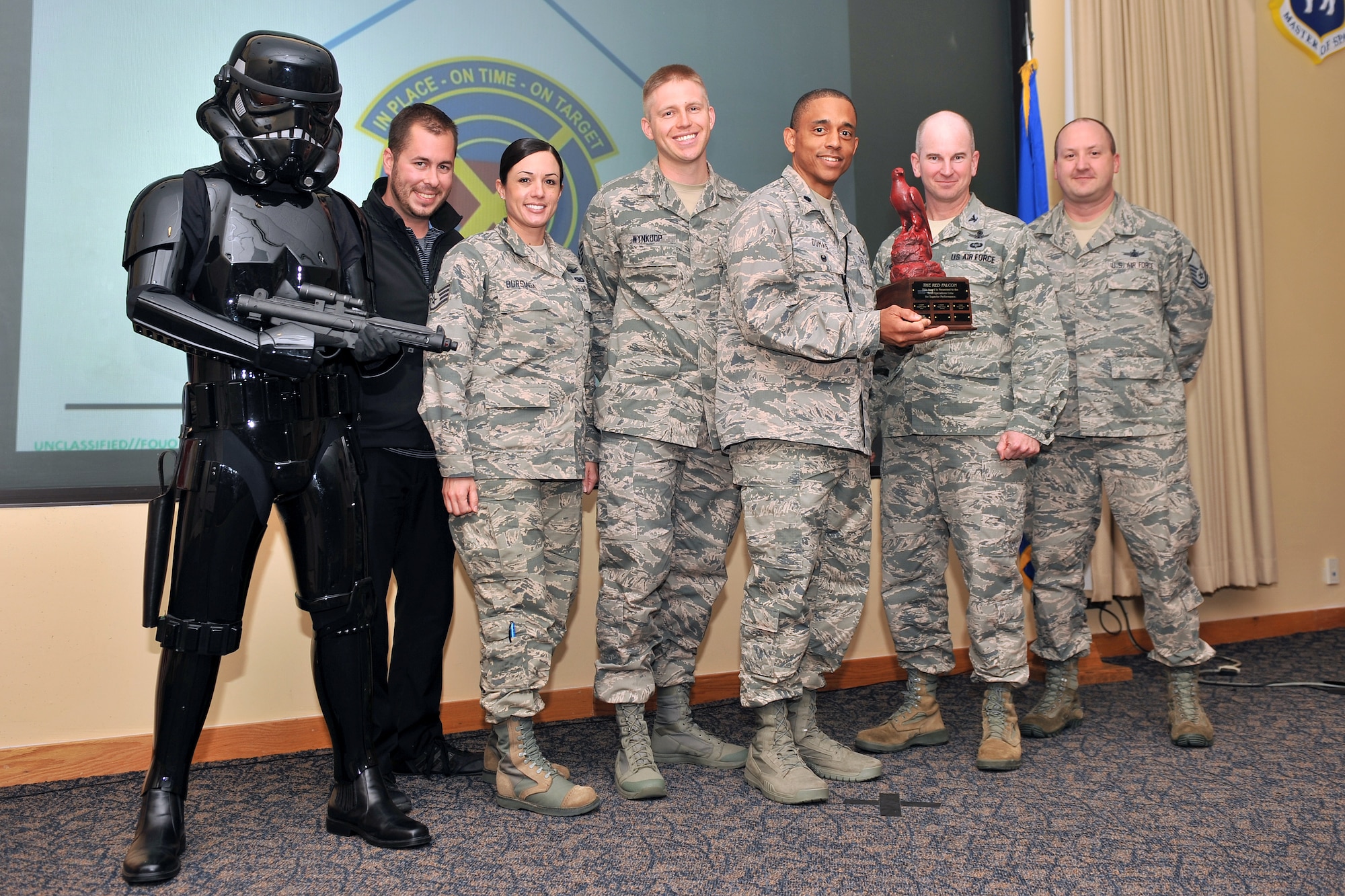 Colonel Dennis Bythewood, 50th Operations Group commander, presents the RED FALCON trophy to the 19th Space Operations Squadron Gator crew in a ceremony last month at Schriever Air Force Base, Colo. RED FALCON is a 50 OG competition designed to inspire 50th Space Wing crews to think critically when operating in contested, degraded and operationally limited environments. (U.S. Air Force/Dennis Rogers)  