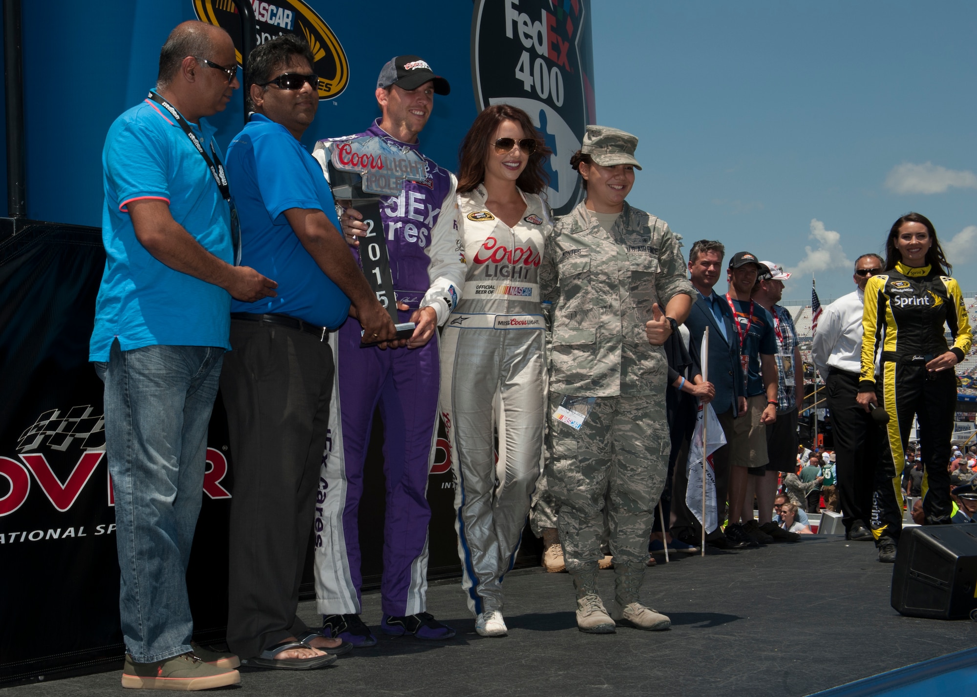 Airman 1st Class Karla Montes, 436th Dental Squadron dental assistant, right, presented Denny Hamlin, driver of the No. 11 FedEx Toyata, the Coors Light Pole trophy for the FedEx 400 Benefiting Autism Speaks NASCAR race May 31, 2015, at Dover International Speedway in Dover, Del. Montes was also honored as an honorary pit crew member. (U.S. Air Force photo/Airman 1st Class Zachary Cacicia)