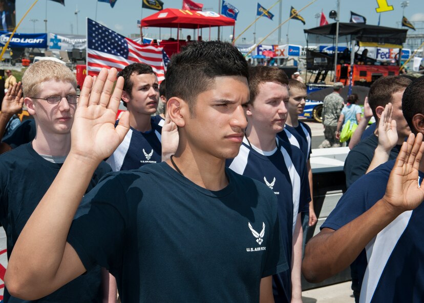 Eric Feliciano, son of U.S. Army Sgt. 1st Class Elmer Feliciano, Air Force Mortuary Affairs Operations Army liaison notification officer, raises his hand during the oath of enlistment May 31, 2015, at Dover International Speedway in Dover, Del. Feliciano will depart for Air Force Basic Military Training on July 28, 2015. (U.S. Air Force photo/Airman 1st Class Zachary Cacicia)